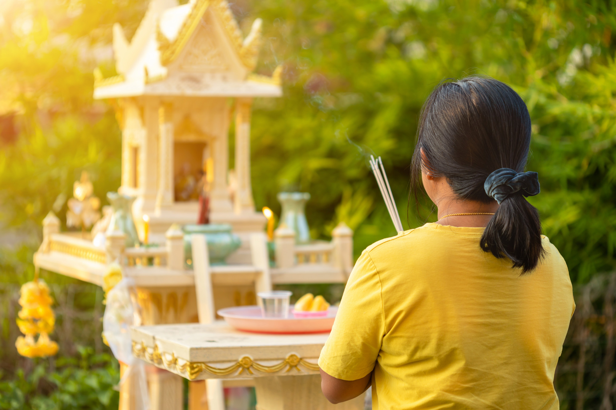 back side thai woman standing front joss house praying with incense